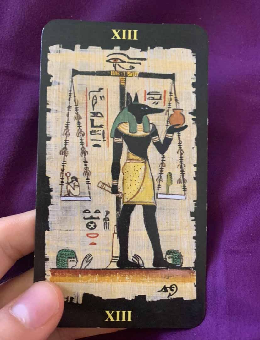 Egyptian tarot card held in a hand with purple backdrop